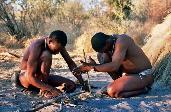 Two San men demonstrating how to start a fire by rubbing sticks