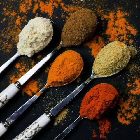 Differently coloured spices heaped on decorative spoons