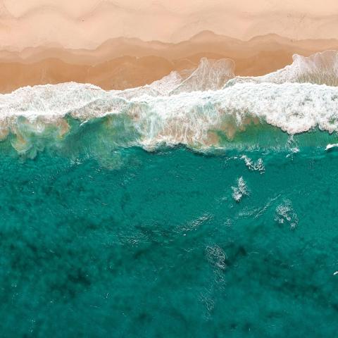aerial view of a coastline where blue ocean waves meet a sandy beach