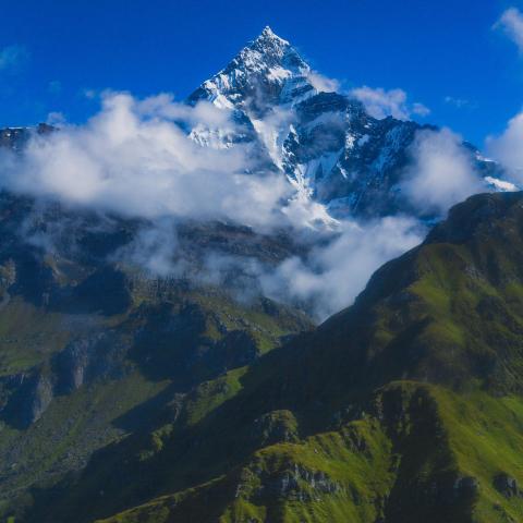 the majestic Himalayan landscape in Nepal, with towering snow-capped peaks and lush green slopes.